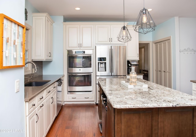 kitchen featuring sink, tasteful backsplash, decorative light fixtures, appliances with stainless steel finishes, and a kitchen island