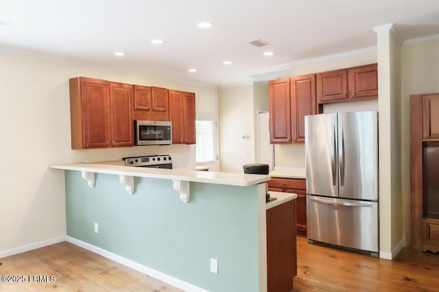 1003 9th St, Port Royal, SC 29935 - kitchen featuring stainless steel appliances, a breakfast bar, light countertops, a peninsula, and ornamental molding
