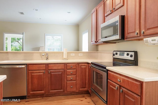 1003 9th St, Port Royal, SC 29935 - kitchen featuring appliances with stainless steel finishes, light wood-style flooring, crown molding, light countertops, and a peninsula