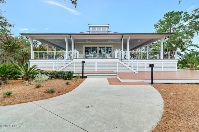 view of front facade featuring covered porch, a ceiling fan, a standing seam roof, metal roof, and stairs