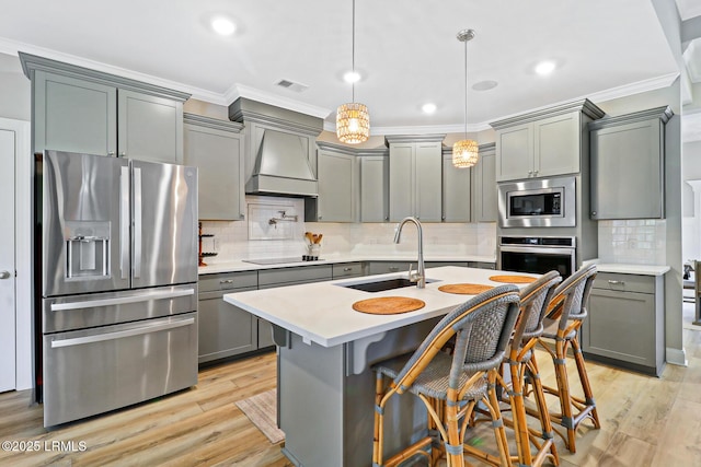 kitchen featuring stainless steel appliances, crown molding, gray cabinetry, premium range hood, and a sink