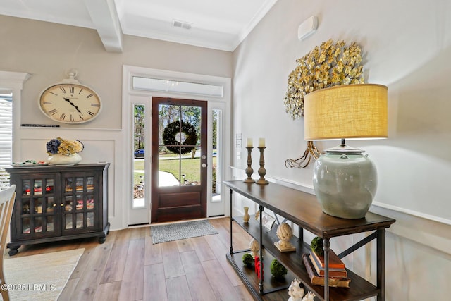 foyer featuring crown molding, visible vents, and wood finished floors