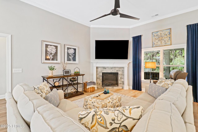 living room featuring ornamental molding, a fireplace, wood finished floors, and visible vents