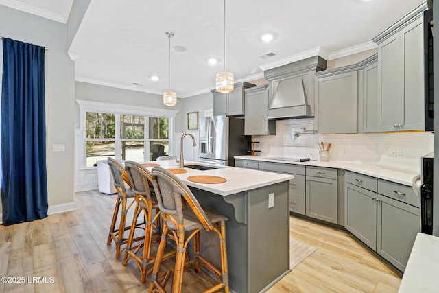 kitchen with ornamental molding, gray cabinets, premium range hood, stainless steel refrigerator with ice dispenser, and backsplash