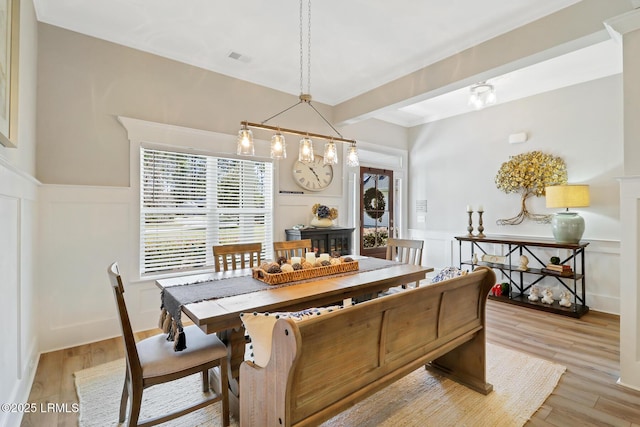 dining space with a healthy amount of sunlight, light wood finished floors, and a decorative wall