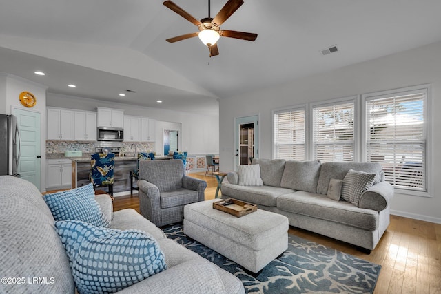 living room with ceiling fan, vaulted ceiling, and wood-type flooring