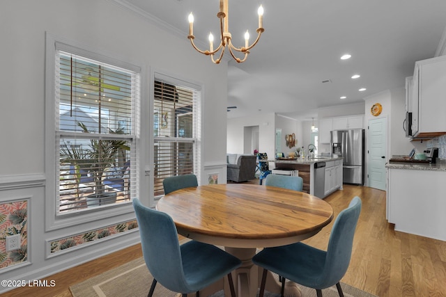 dining room featuring an inviting chandelier, ornamental molding, sink, and light hardwood / wood-style floors