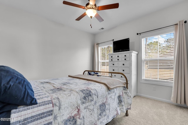 bedroom with ceiling fan, light colored carpet, and multiple windows