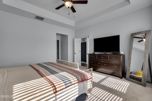 bedroom featuring ornamental molding, light colored carpet, ceiling fan, and a tray ceiling