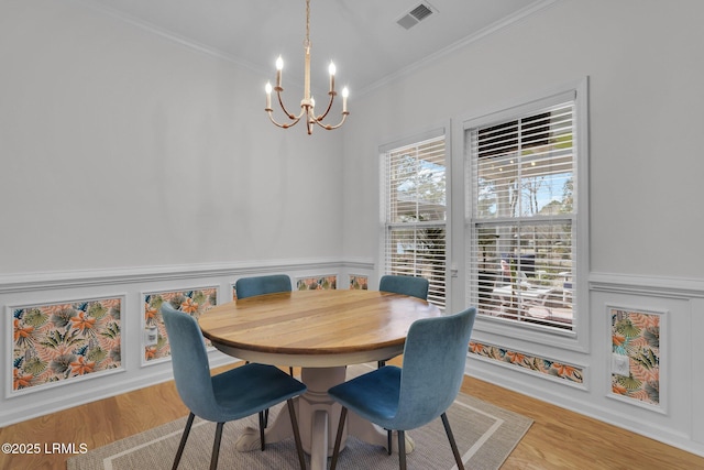 dining room with ornamental molding, a chandelier, and light hardwood / wood-style flooring