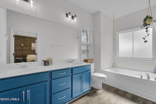 bathroom with hardwood / wood-style flooring, vanity, toilet, and a bathing tub