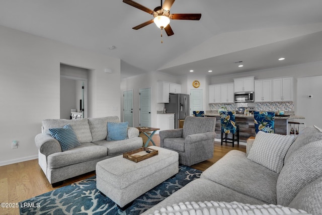 living room with lofted ceiling, ceiling fan, and light wood-type flooring