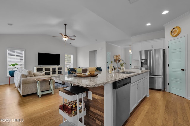 kitchen featuring sink, a kitchen island with sink, stainless steel appliances, light stone counters, and white cabinets