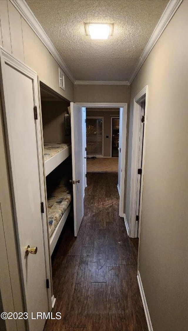 hallway with dark hardwood / wood-style flooring, crown molding, and a textured ceiling