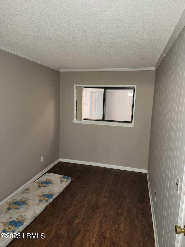 unfurnished room with crown molding, dark wood-type flooring, and a textured ceiling