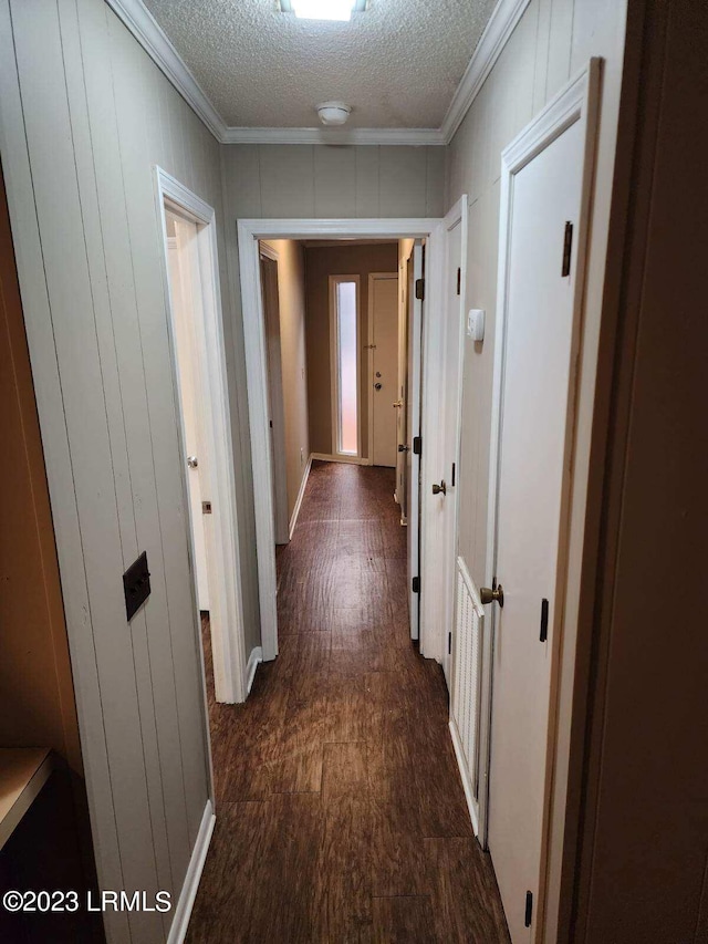 corridor with crown molding, dark wood-type flooring, and a textured ceiling