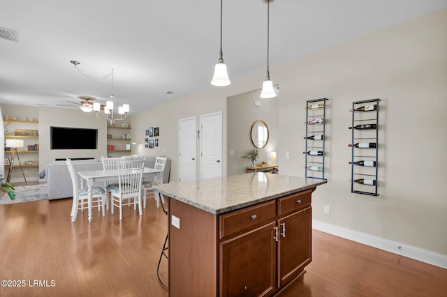 1216 Hearthstone Dr, Ridgeland, SC 29936 - kitchen featuring a center island, wood finished floors, hanging light fixtures, and light stone counters