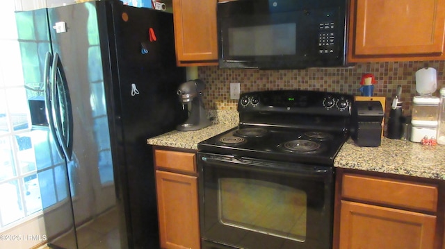 409 Dante Cir, Beaufort, SC 29906 - kitchen with brown cabinets, light stone countertops, black appliances, and backsplash