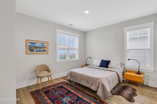 bedroom with wood finished floors, visible vents, and baseboards