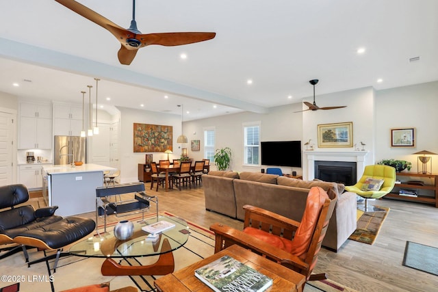 living area featuring light wood-style floors, a glass covered fireplace, and recessed lighting