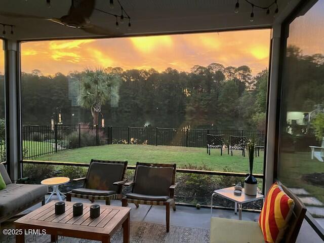 patio terrace at dusk with ceiling fan, a yard, outdoor lounge area, and fence