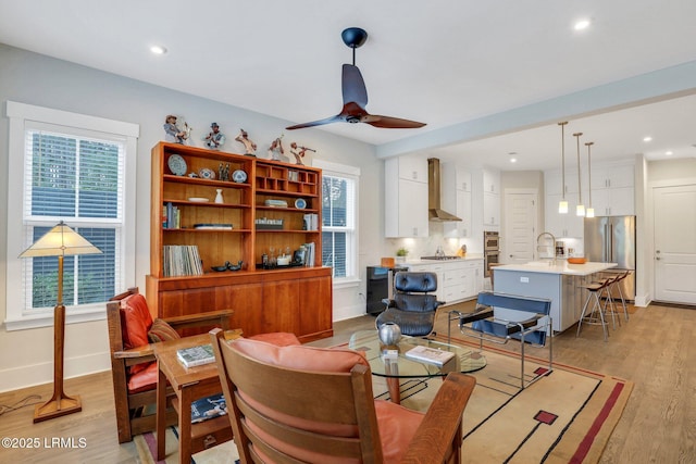 living room featuring ceiling fan, light wood-style flooring, and baseboards