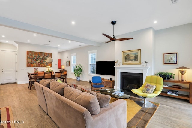 living area featuring recessed lighting, baseboards, a fireplace, and light wood finished floors