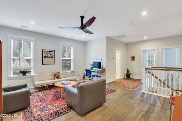 living area with visible vents, plenty of natural light, wood finished floors, and attic access