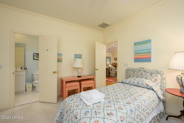 bedroom featuring ensuite bath, ornamental molding, and light colored carpet