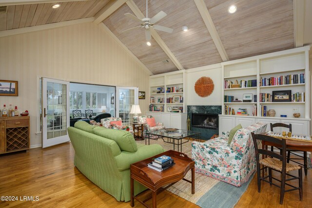 living room featuring beam ceiling, high vaulted ceiling, light hardwood / wood-style flooring, built in features, and a premium fireplace