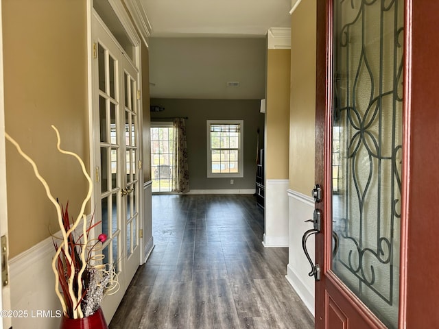 entryway with dark wood finished floors, visible vents, crown molding, and baseboards