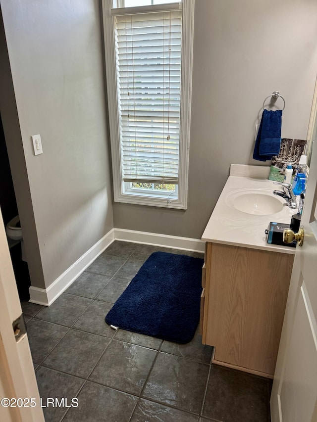 bathroom featuring baseboards, toilet, vanity, and tile patterned flooring