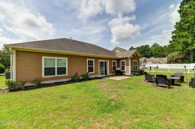 rear view of house with a patio, a yard, fence, and a shingled roof