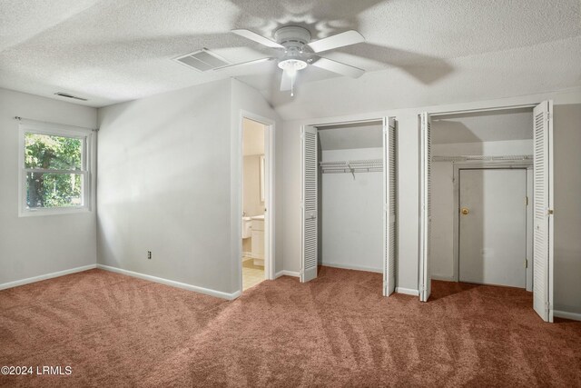 unfurnished bedroom with two closets, carpet floors, connected bathroom, and ceiling fan