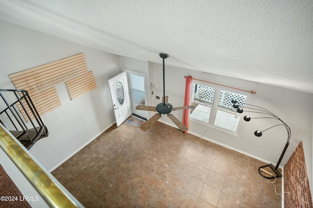 interior space featuring tile patterned flooring, vaulted ceiling, and a textured ceiling