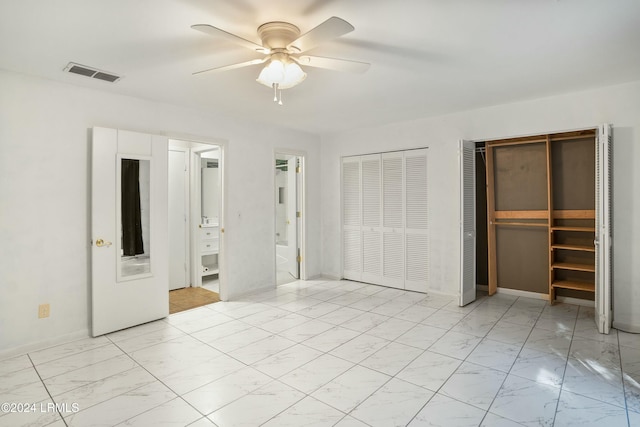 unfurnished bedroom featuring multiple closets and ceiling fan