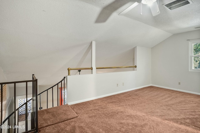 bonus room featuring lofted ceiling, ceiling fan, a textured ceiling, and carpet flooring