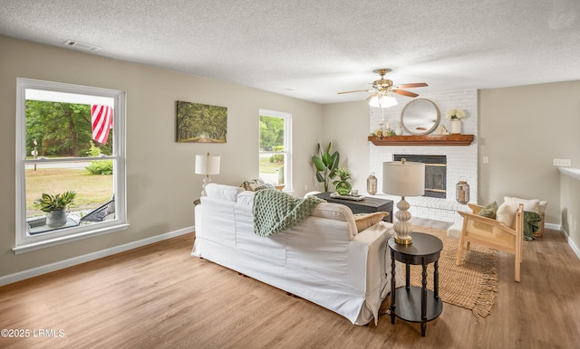 46 Mroz Rd, Beaufort, SC 29906 - living room featuring wood finished floors, baseboards, a textured ceiling, ceiling fan, and a fireplace