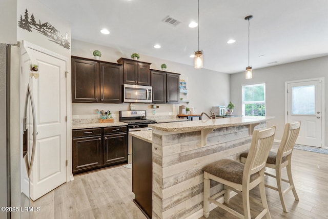 13 Hager Rd, Bluffton, SC 29910 - kitchen featuring dark brown cabinetry, light wood-style flooring, light stone countertops, visible vents, and appliances with stainless steel finishes