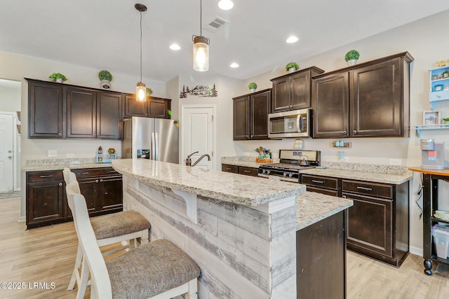 13 Hager Rd, Bluffton, SC 29910 - kitchen with dark brown cabinetry, light wood-type flooring, light stone countertops, appliances with stainless steel finishes, and hanging light fixtures