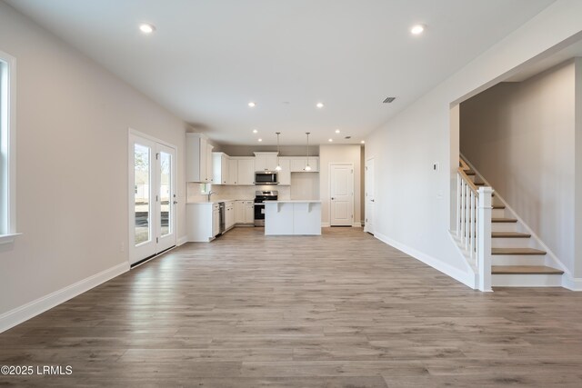 kitchen with sink, a center island, hanging light fixtures, appliances with stainless steel finishes, and light stone countertops