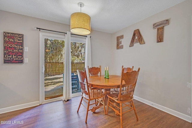 dining room with dark wood-style floors, a textured ceiling, and baseboards