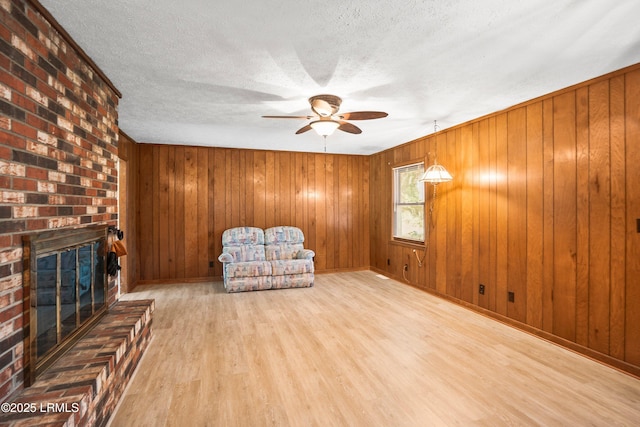 806 Coates Ln, Beaufort, SC 29902 - unfurnished room featuring wood finished floors, ceiling fan, a fireplace, a textured ceiling, and wooden walls