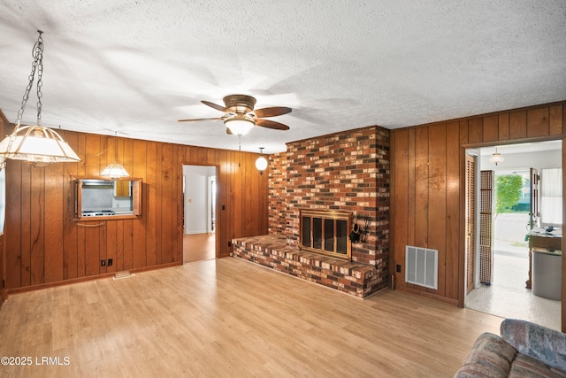 806 Coates Ln, Beaufort, SC 29902 - unfurnished living room with wood finished floors, a ceiling fan, wooden walls, a fireplace, and a textured ceiling