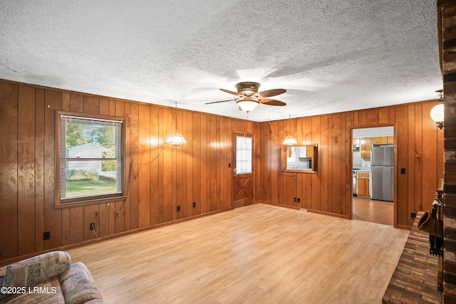 806 Coates Ln, Beaufort, SC 29902 - unfurnished living room with wood finished floors, a ceiling fan, wooden walls, baseboards, and a textured ceiling