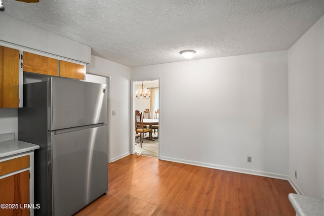 806 Coates Ln, Beaufort, SC 29902 - kitchen with freestanding refrigerator, brown cabinets, a chandelier, light wood-style floors, and light countertops