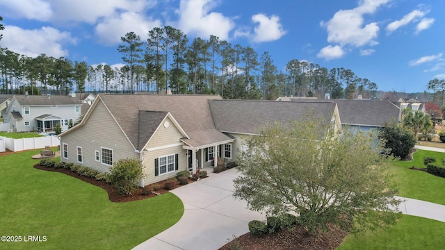 view of front of home with a shingled roof, concrete driveway, a residential view, fence, and a front lawn