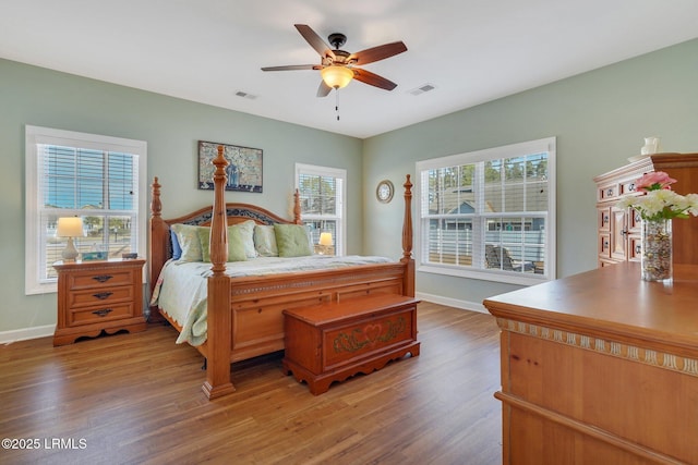 bedroom with a ceiling fan, baseboards, visible vents, and wood finished floors