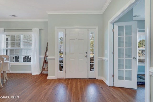 entryway with ornamental molding, wood finished floors, visible vents, and baseboards