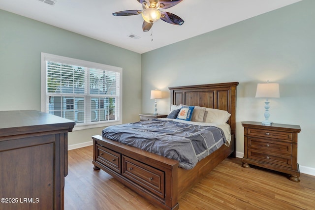 bedroom with a ceiling fan, light wood-type flooring, visible vents, and baseboards